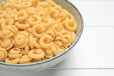 Photo of Raw dischi volanti pasta in bowl on white wooden table, closeup