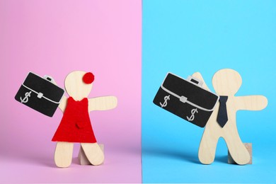 Photo of Gender pay gap. Wooden figures of man and woman with bags on color background