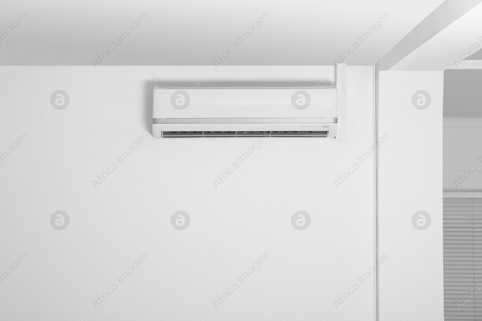 Photo of Modern air conditioner on white wall indoors