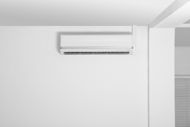 Photo of Modern air conditioner on white wall indoors