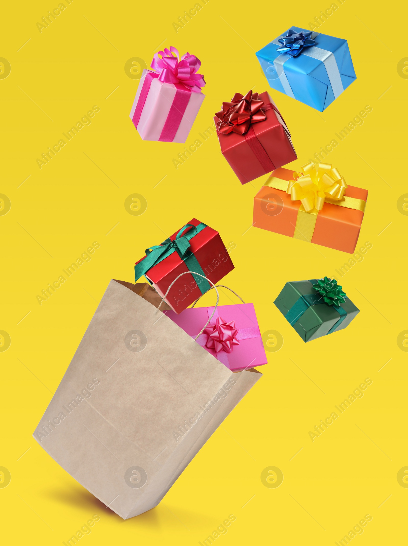 Image of Many different gift boxes falling into paper shopping bag on yellow background