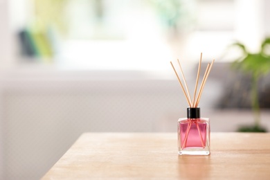 Photo of Aromatic reed air freshener on table indoors