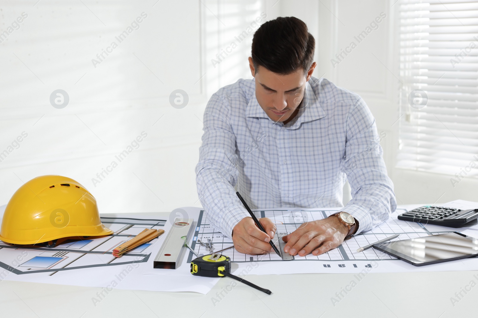 Photo of Architect working with construction drawings in office