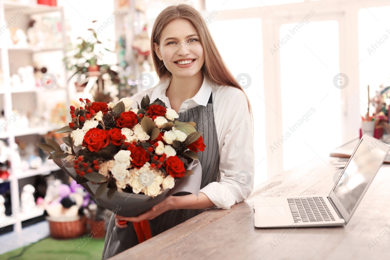 Photo of Female florist holding bouquet flowers at workplace