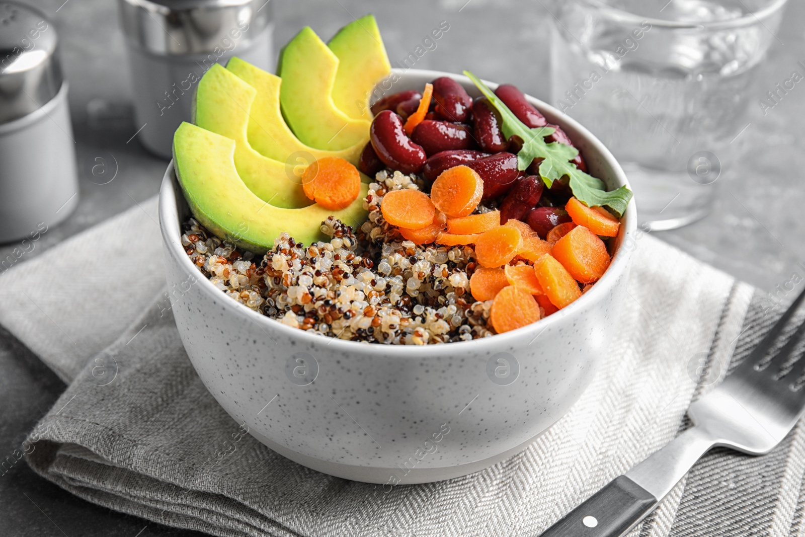 Photo of Healthy quinoa salad with vegetables in bowl served on table