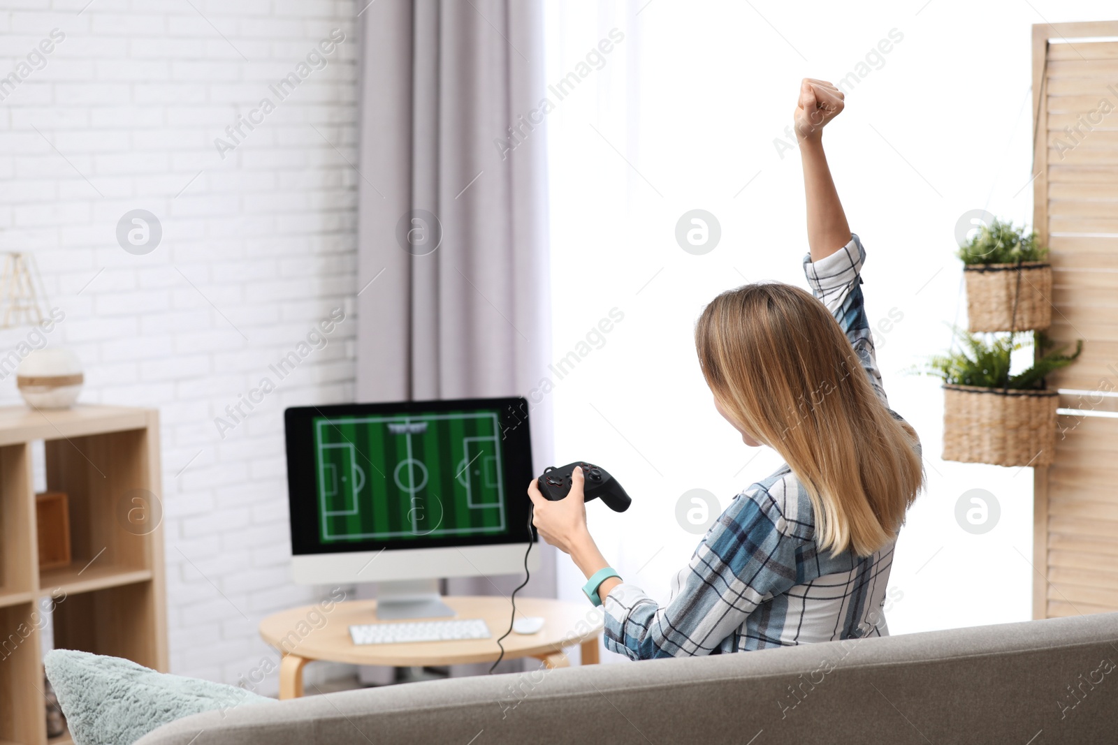 Photo of Young woman playing video game at home