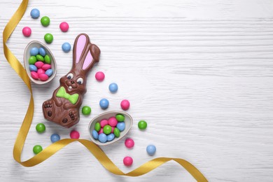 Photo of Flat lay composition with chocolate bunny on white wooden table, space for text. Easter celebration