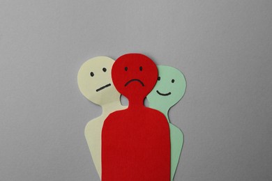 Photo of Colorful paper cutouts of person with different emotions on grey background, top view