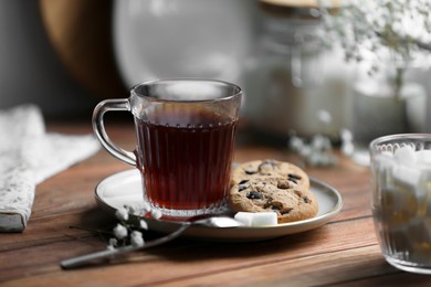 Cup of freshly brewed tea and delicious cookies on wooden table