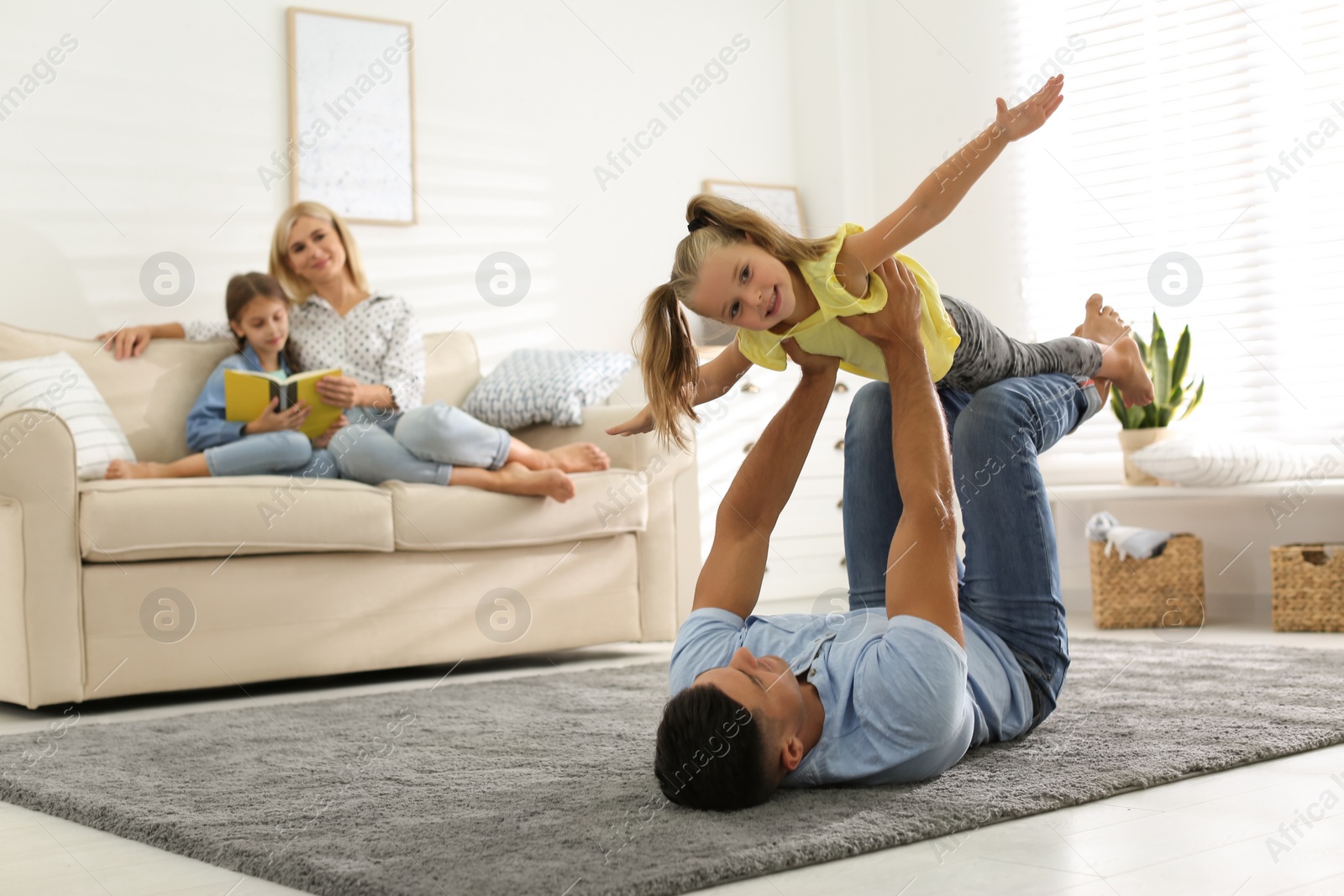 Photo of Happy father playing with his daughter on floor at home