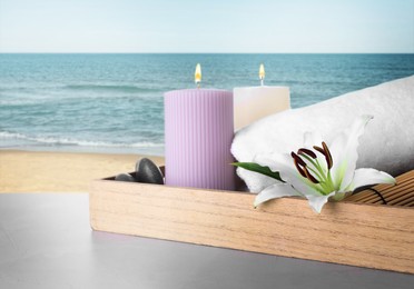 Image of Tray with flower and spa supplies on table against seascape