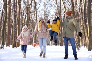 Happy family walking in sunny snowy forest