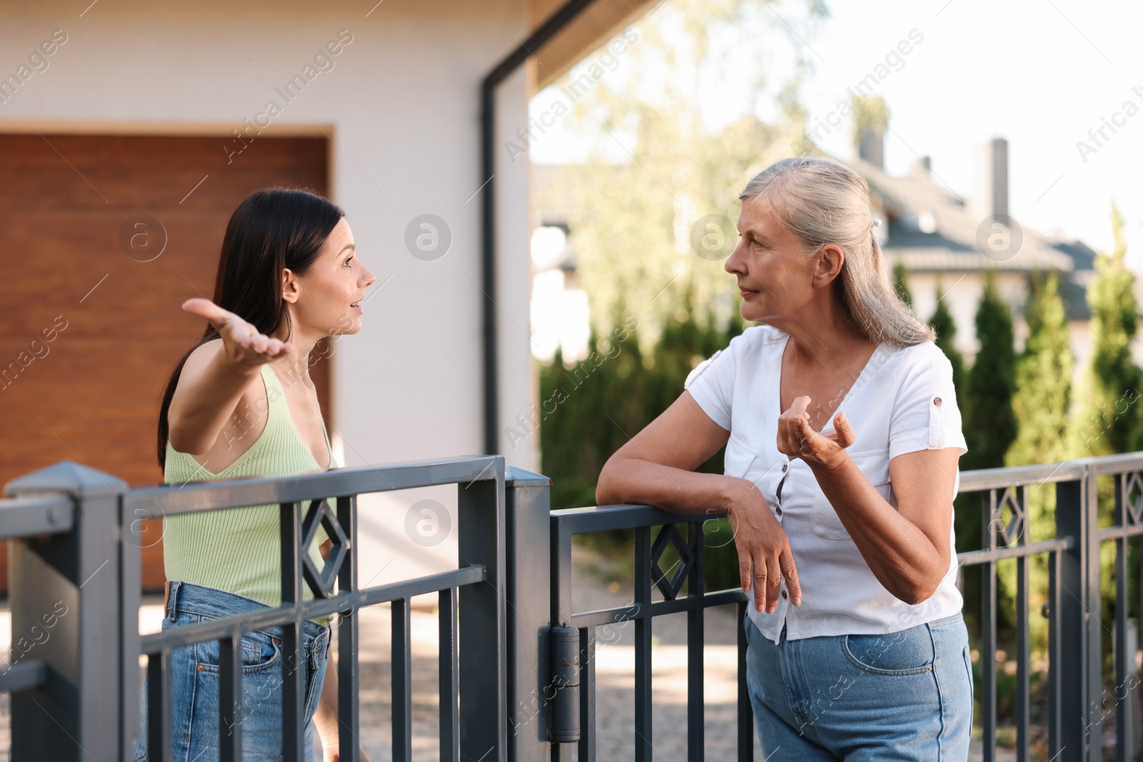 Photo of Emotional neighbours having argument near fence outdoors