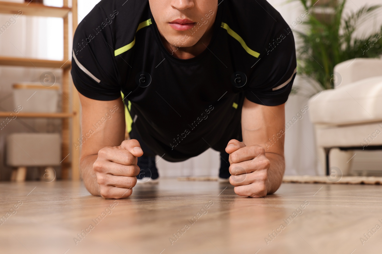 Photo of Man doing plank exercise on floor at home, closeup