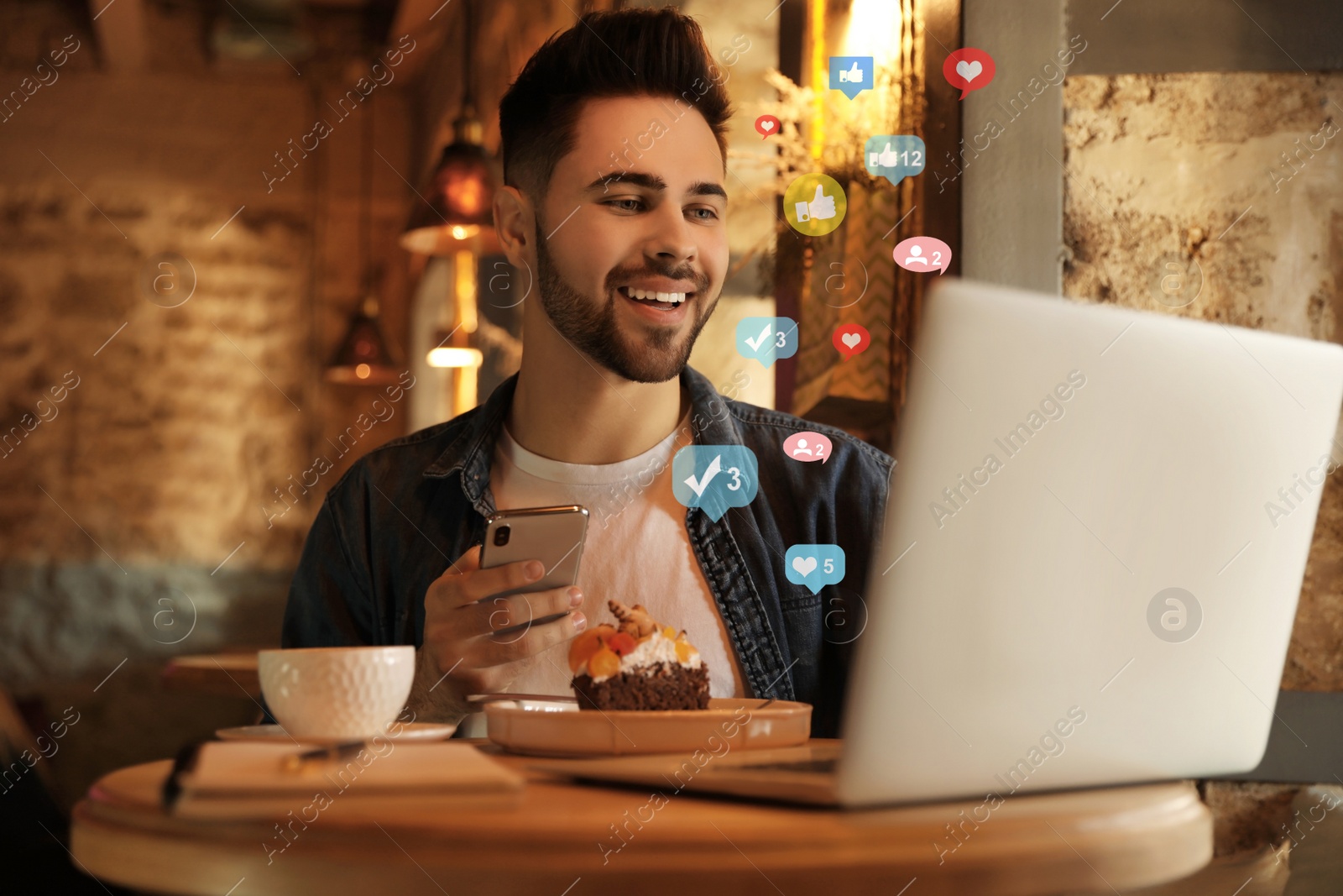 Image of Young blogger with laptop and phone at table in cafe