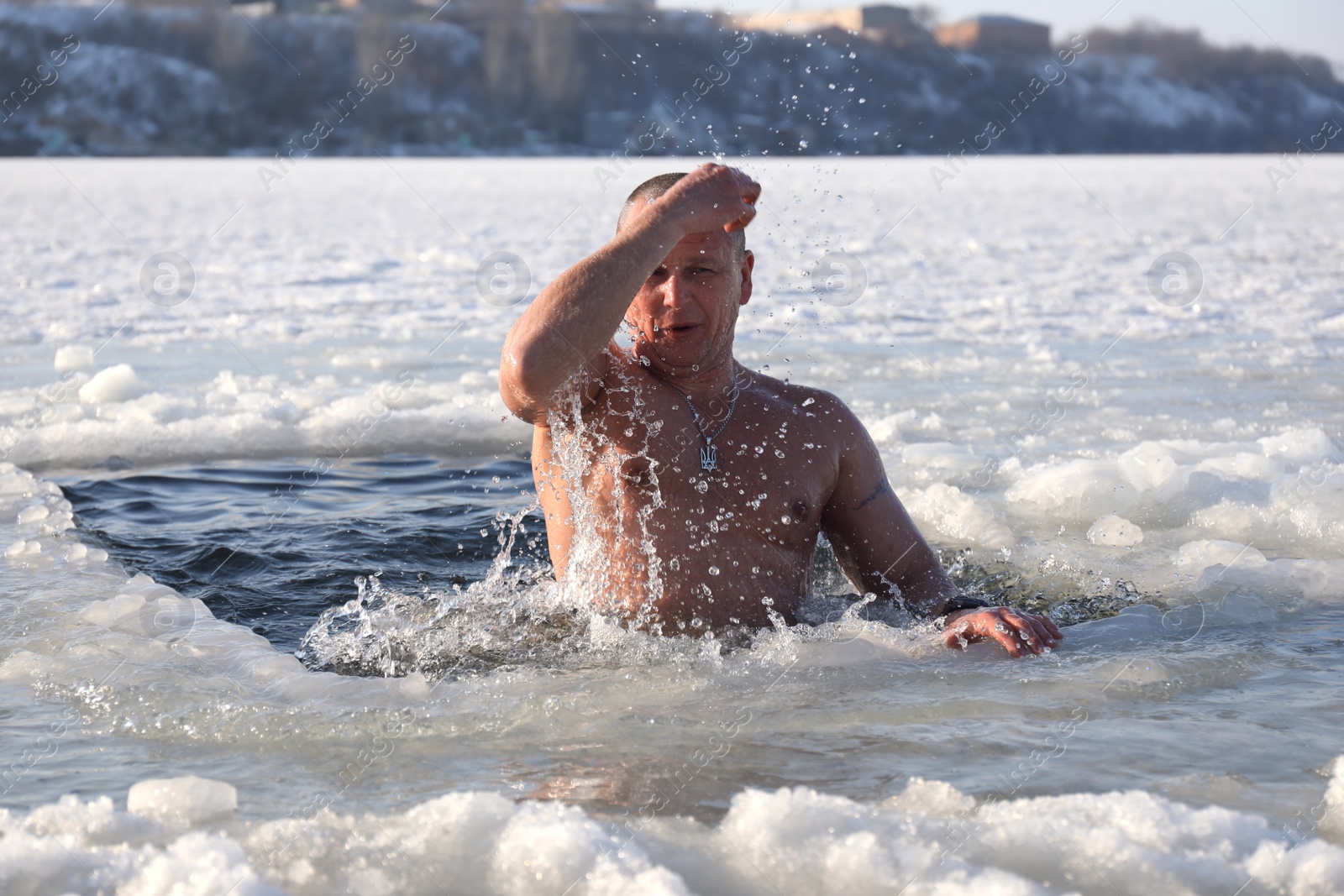 Photo of MYKOLAIV, UKRAINE - JANUARY 06, 2021: Man immersing in icy water on winter day