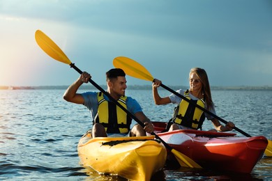 Couple in life jackets kayaking on river. Summer activity