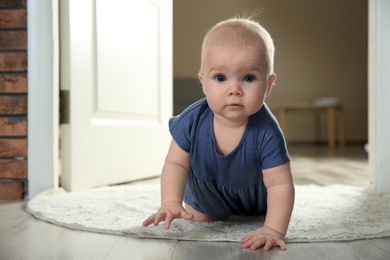 Cute little baby crawling on rug indoors