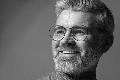 Portrait of smiling man on grey background, space for text. Black and white effect