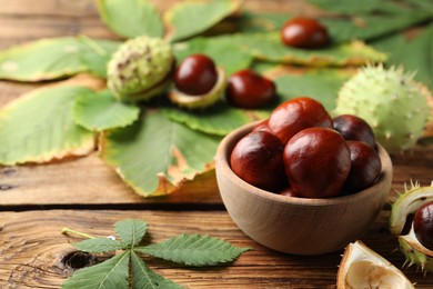 Photo of Horse chestnuts and leaves on wooden table