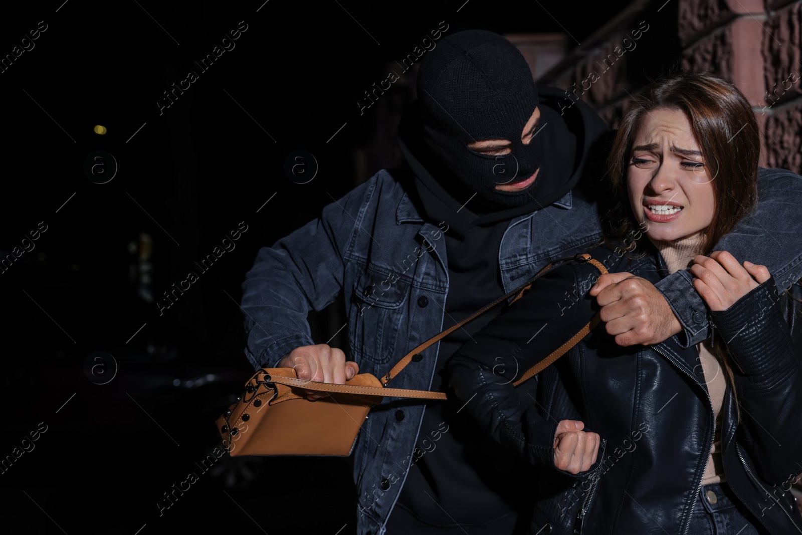 Photo of Woman fighting with thief while he trying to steal her bag outdoors at night. Self defense concept