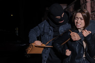 Photo of Woman fighting with thief while he trying to steal her bag outdoors at night. Self defense concept