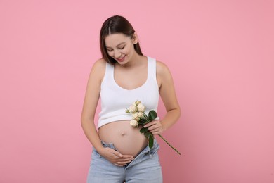 Beautiful pregnant woman with roses on pink background
