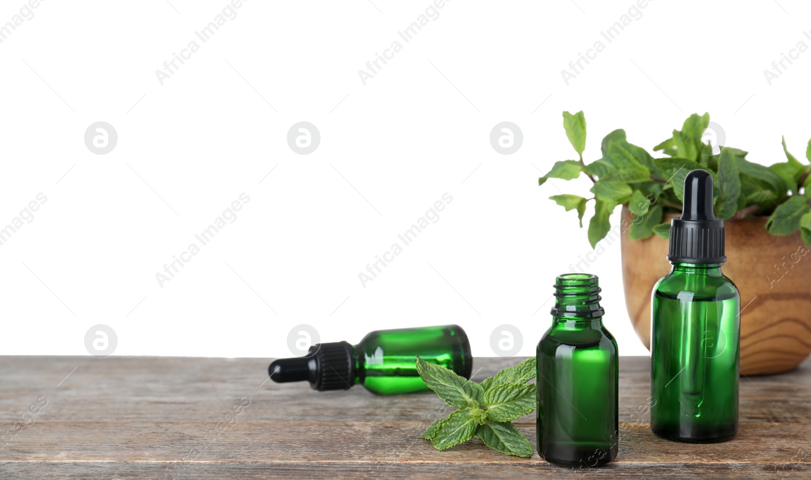 Photo of Bottles of mint essential oil on wooden table against white background. Space for text