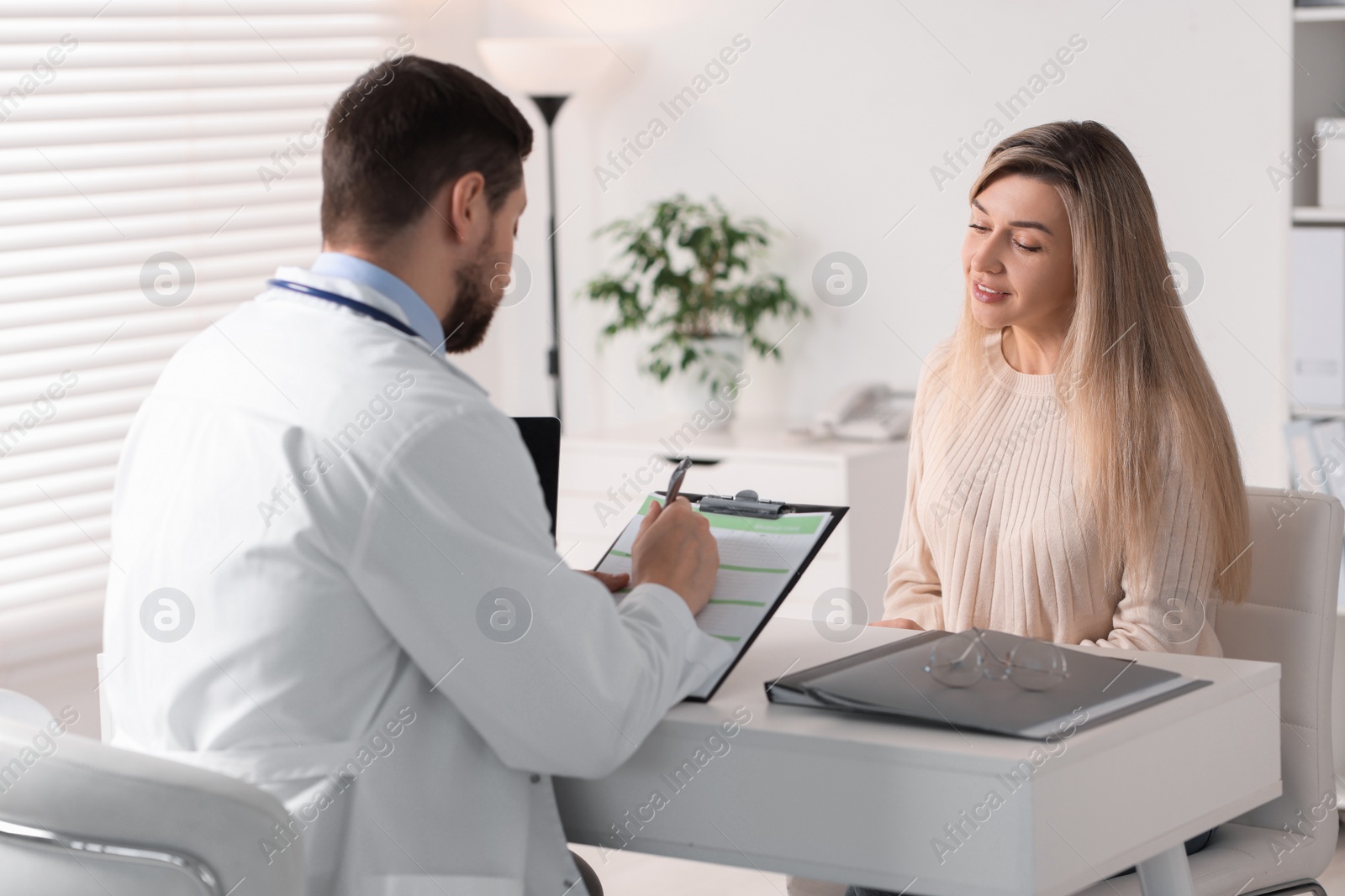 Photo of Professional doctor working with patient at white table in hospital