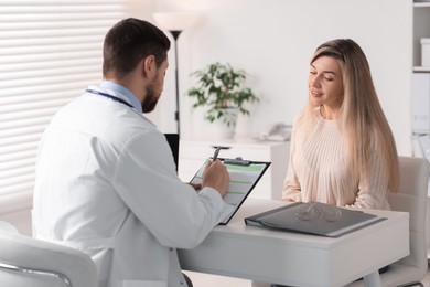 Professional doctor working with patient at white table in hospital