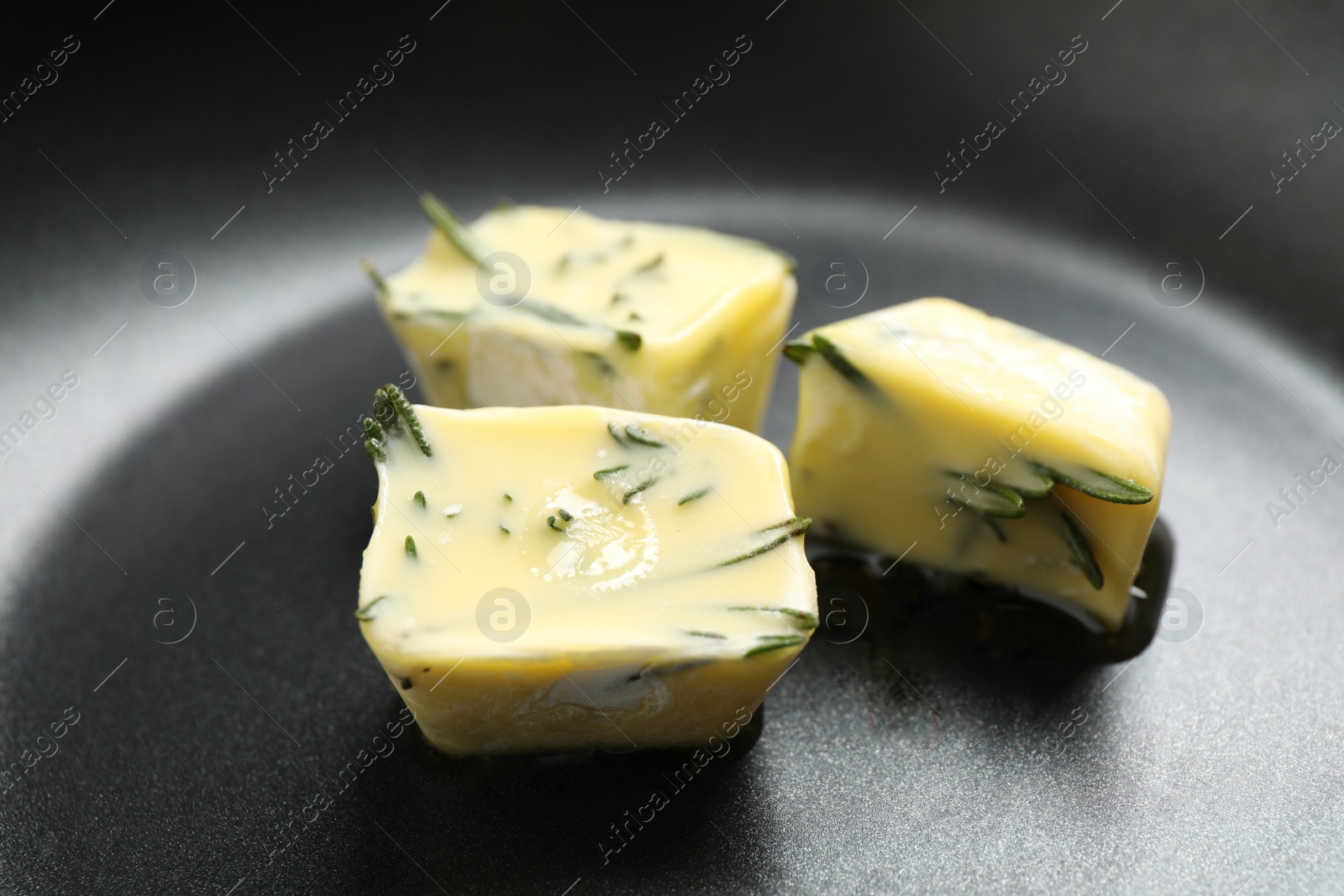 Photo of Melting ice cubes with oil and rosemary on frying pan, closeup