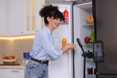 Smiling food blogger explaining something while recording video in kitchen