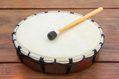Photo of Modern drum with drumstick on wooden table. Percussion musical instrument