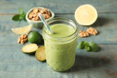 Photo of Fresh feijoa smoothie in glass on wooden table, closeup
