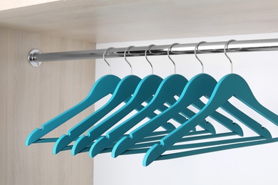 Photo of Clothes hangers on metal rail in wardrobe