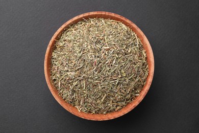 Photo of Wooden bowl with dried thyme on grey background, top view