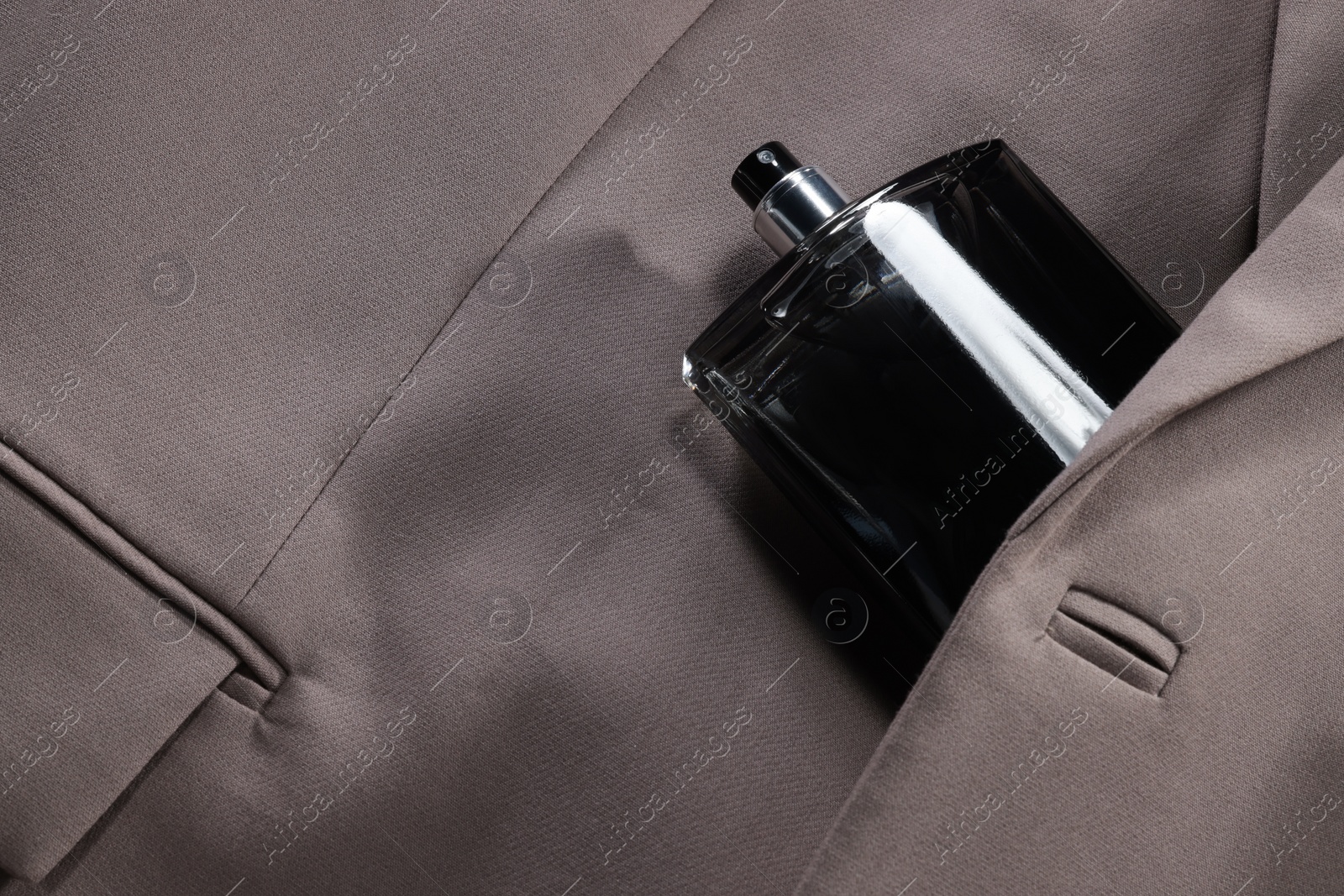 Photo of Luxury men's perfume in bottle on beige jacket, above view. Space for text