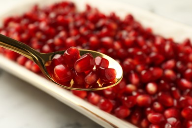 Photo of Eating ripe juicy pomegranate grains at table, closeup