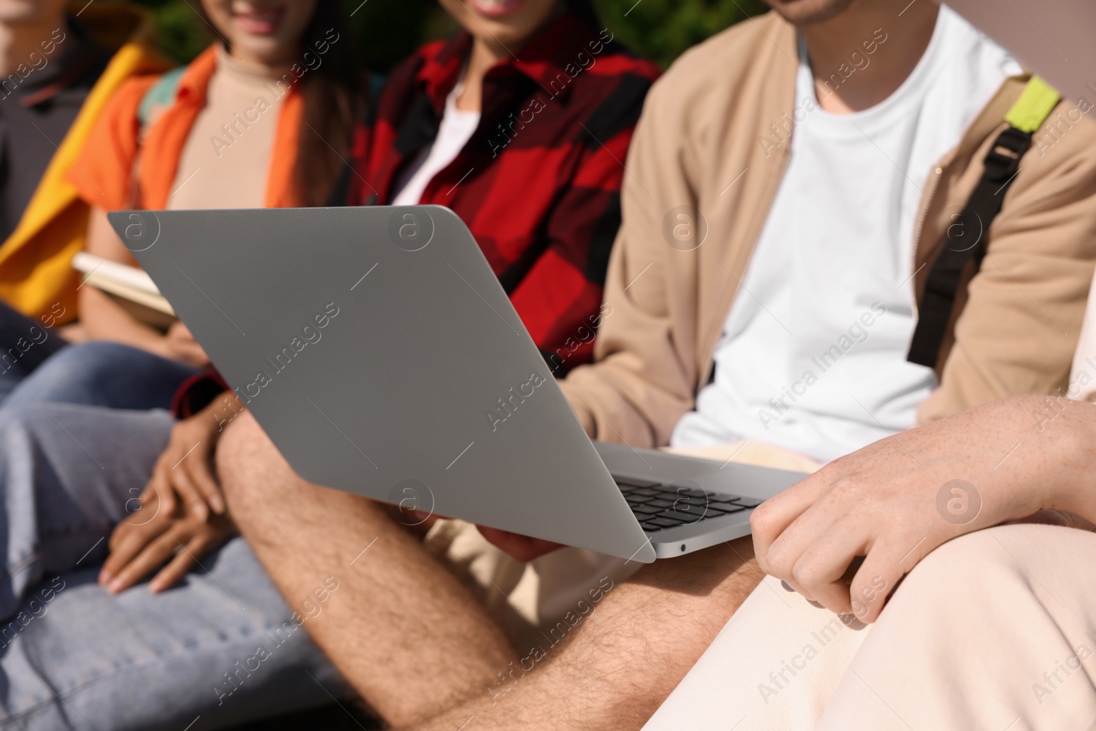 Photo of Group of students studying with laptop together outdoors, closeup
