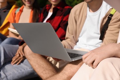 Group of students studying with laptop together outdoors, closeup