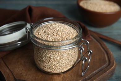 Photo of Jar with white quinoa on wooden board