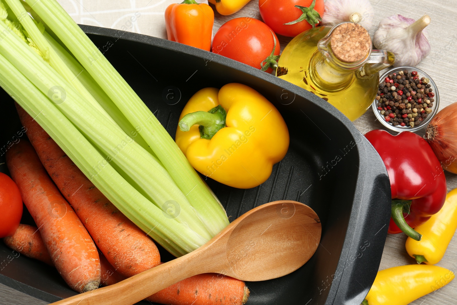 Photo of Black pot, spoon and fresh products on wooden table, top view