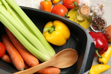 Photo of Black pot, spoon and fresh products on wooden table, top view