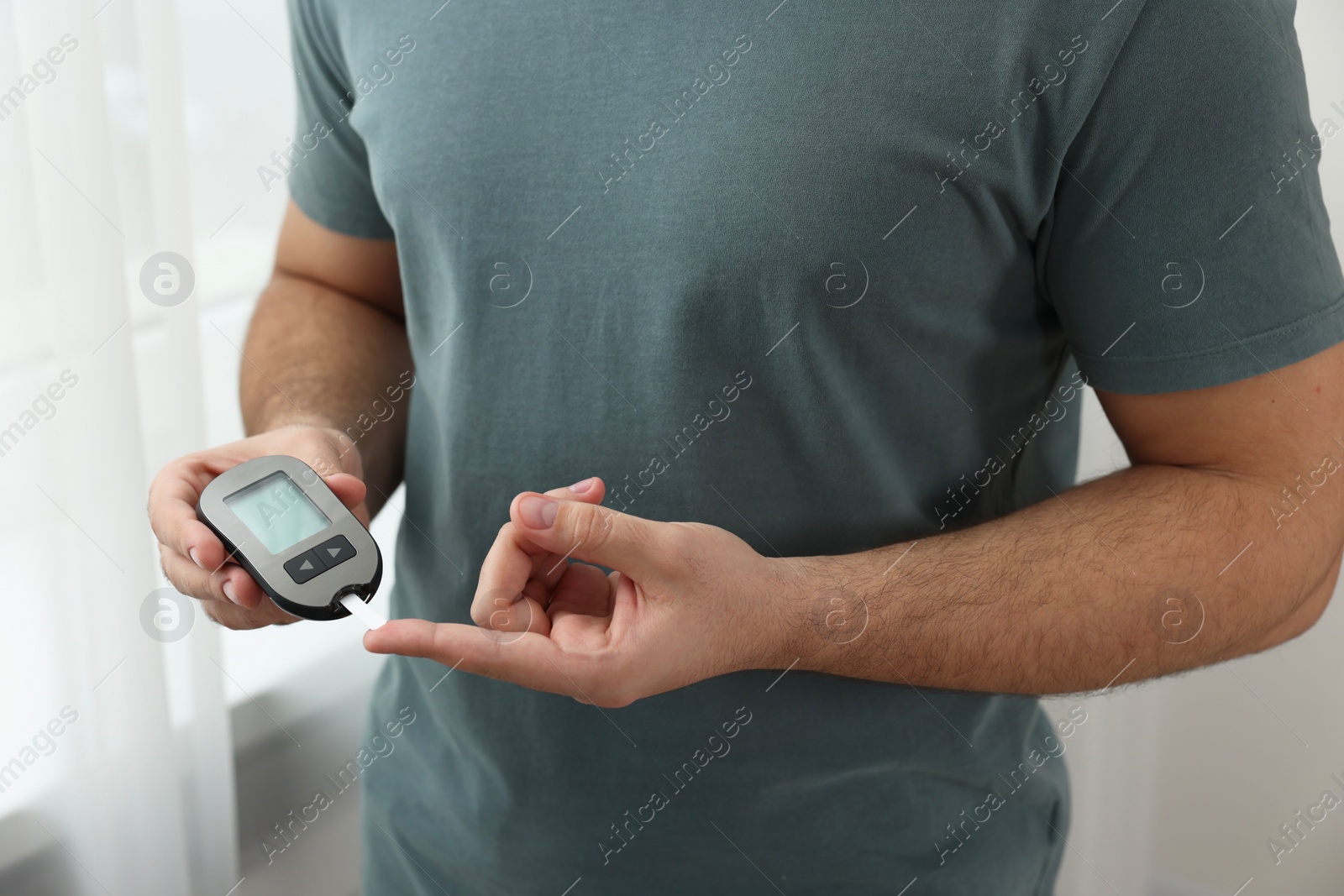 Photo of Diabetes test. Man checking blood sugar level with glucometer at home, closeup