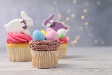 Photo of Tasty decorated Easter cupcakes on wooden table, space for text