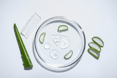 Photo of Cut aloe vera and drops of cosmetic gel on light background, flat lay