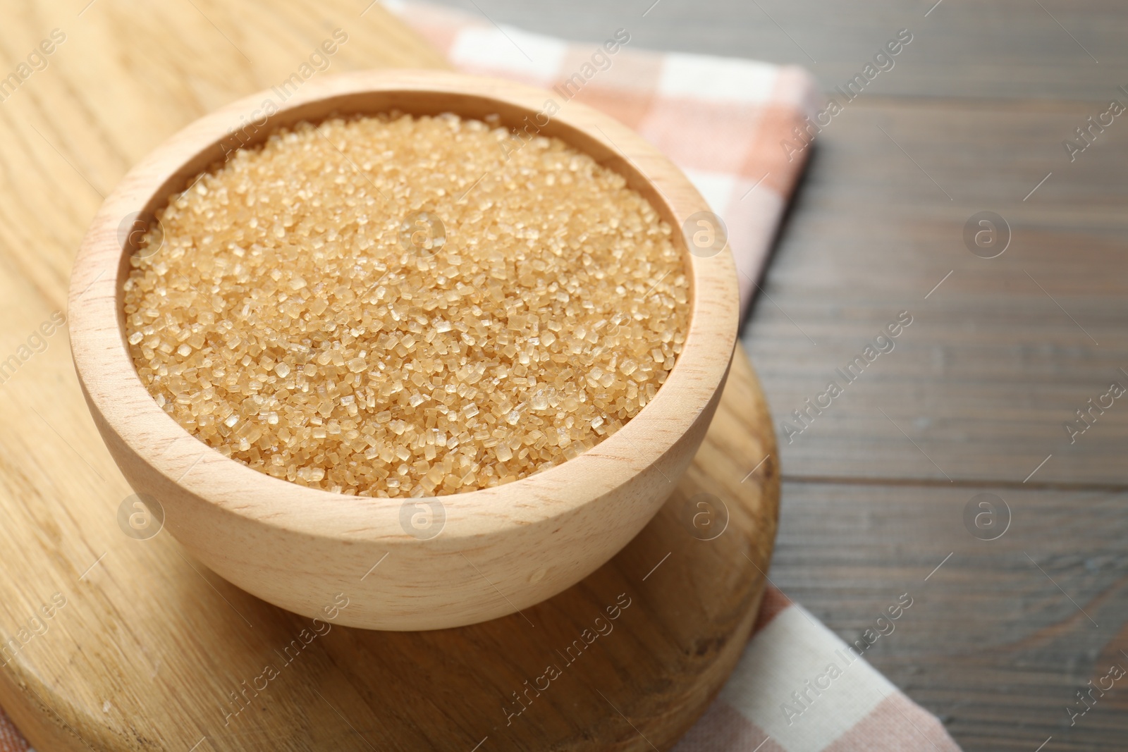 Photo of Brown sugar in bowl on wooden table, closeup