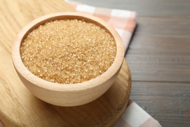 Photo of Brown sugar in bowl on wooden table, closeup