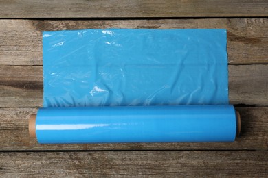 Photo of Roll of plastic stretch wrap film on wooden table, top view