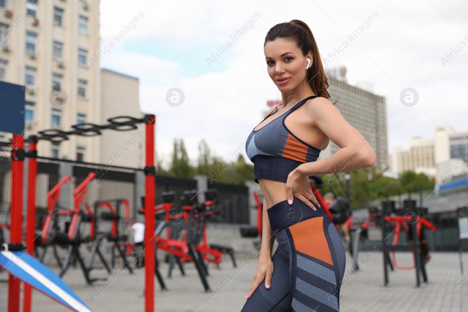 Photo of Beautiful woman with earphones wearing fitness clothes near outdoor gym